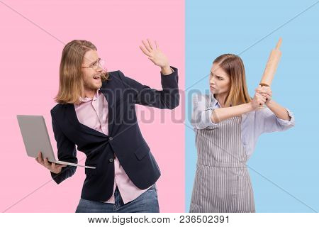Do Not Hit Me. Pleasant Young Businessman Holding A Laptop And Dodging His Wifes Rolling Pin While S