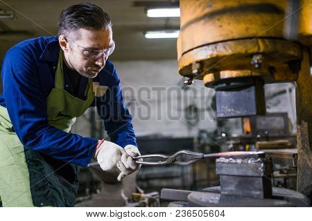 The Smith Works With An Electric Hammer.