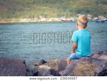 Cute caucasian boy at seaside. Rear view. Leisure time