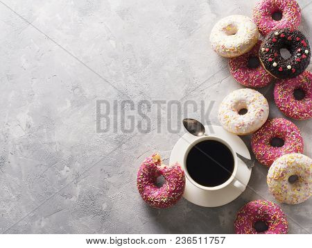 Sone Pink And White Donuts With Cup Of Coffee Over Grey Stone Texture, Top View, Copy Space