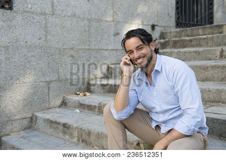 Young Attractive Latin Man On City Staircase Talking Happy On Mobile Phone Looking Satisfied And Con