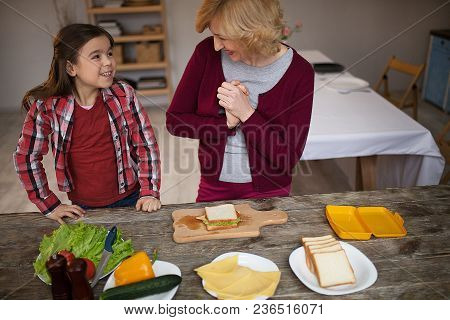 Cmiling Grandma And Granddaughter Looking At Each Other. Cooked Sandwich Together.