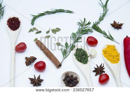 Cooking Hot Spicy Food Concept. Dry Spices And Herbs In Wooden Spoons, Fresh Herbs, Cloves And Cherr