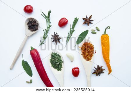 Cooking Hot Spicy Food Concept. Dry Spices And Herbs In Wooden Spoons, Fresh Herbs, Cherry Tomatoes 