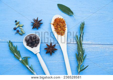Cooking Hot Spicy Food Concept. Dry Spices And Herbs In Wooden Spoons And Cloves On Blue Wooden Back