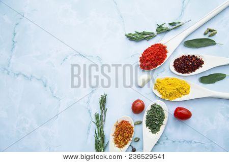 Cooking Hot Spicy Food Concept. Dry Spices And Herbs In Wooden Spoons And Cherry Tomatoes, White Mar