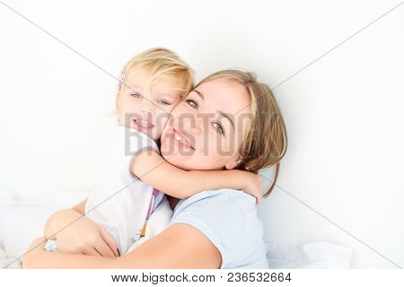 Portraits Of Happy And Loving Mother Embracing Her Daughter On The Bed. Family Morning Concept. Spen