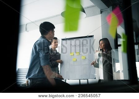 Group Of Young Business People Discussing About Their Business Plan At Modern Startup Office. Meetin