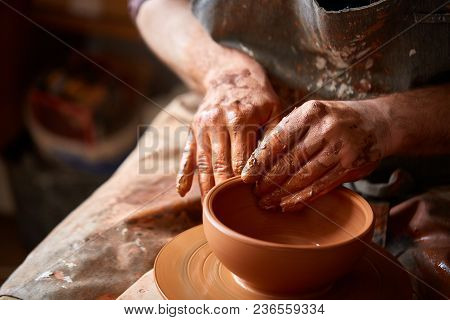 Close-up Hands Of A Male Potter In Plaid Shirt And Dirty Apron Who Molds Bowl From Clay, Selective F