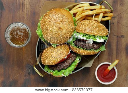 Burgers With Beef Cutlets And French Fries Are Served In A Frying Pan On Wooden Table With Beer And 