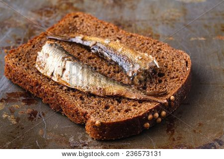 Canned Sprats In Tin Can With Rye Bread. On Rustic Background
