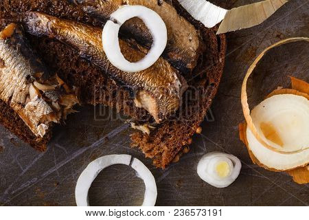 Canned Sprats In Tin Can With Rye Bread. On Rustic Background