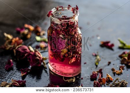 Close Up Of Extracted Rose Water Or Gulab Jal Or Gulab Ka Pani In A Transparent Bottle On Black Surf