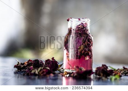 Close Up Of Extracted Rose Water Or Gulab Jal Or Gulab Ka Pani In A Transparent Bottle On Black Surf