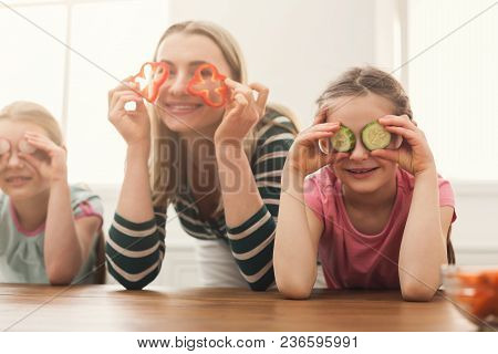 Beautiful Woman With Her Daughters Looks Happy While Cooking Salad Anf Having Fun In The Kitchen Ove