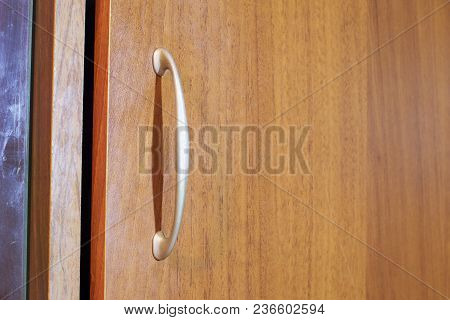 Pull Handle In Arch Style On Edge Of Ajar Cabinet Door Casts Vertical A Sharp Shadow. Frosted Silver