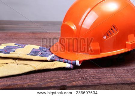 Orange Hard Hat And Gloves For Work On Wood Background