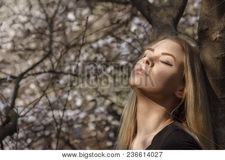 A Girl In The Park Enjoying Warm Sunlight