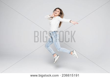 Smiling Young Woman Jumping In Air With Raised Fists Over White Background