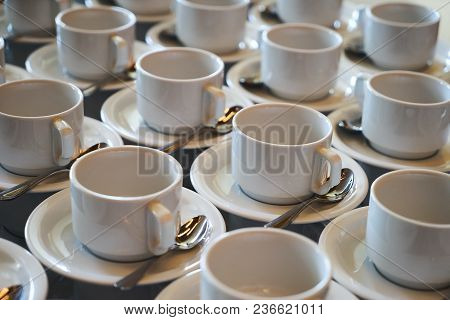 Set Of Empty White Ceramic Tea Or Coffee Cup And Saucers. Group Of Empty Cups Stacked In Rows For Se