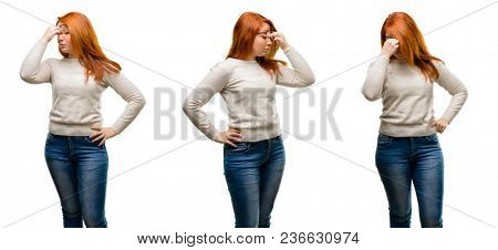 Young Beautiful redhead woman with sleepy expression, being overworked and tired, rubbes nose because of weariness