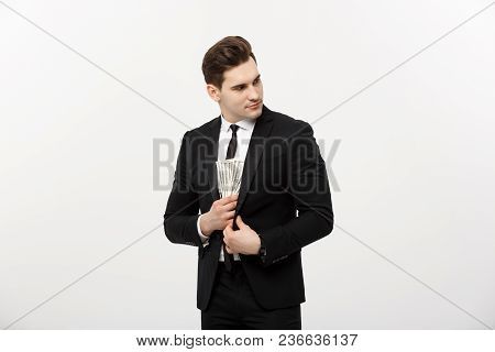 Business Concept: Handsome Businessman In Black Suit Taking Dollars Banknotes With Stealthy Expressi