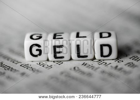 German Word Geld In English Money Formed By Wood Alphabet Blocks On Newspaper Closeup