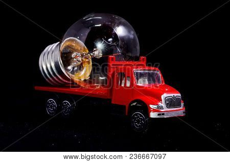 Electric Power Concept Red Truck And Light Bulb On A Black Background