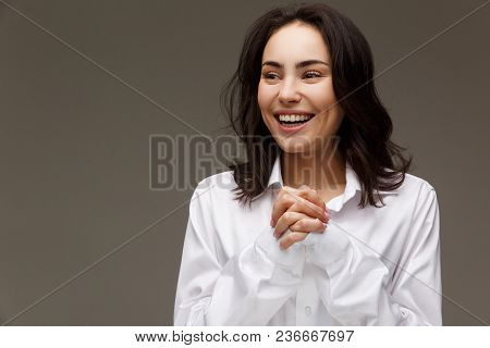 Beautiful Girl In A White Shirt Shows Emotions - Smile, Fun. On A Light Background.