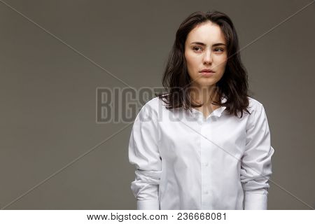 Beautiful Girl In A White Shirt Shows Emotions. On A Light Background.