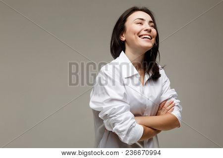 Beautiful Girl In A White Shirt Shows Emotions - Smile, Fun. On A Light Background.