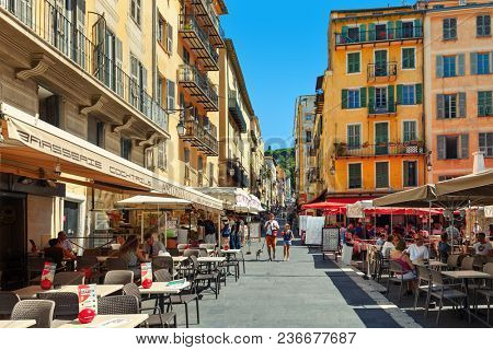 NICE, FRANCE - 02 SEPTEMBER, 2015: People sitting in outdoor restaurants on narrow street in Old town of Nice -  fifth most populous city in France, popular tourist destination.