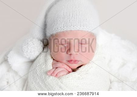 Newborn baby in white wrap laying on basket