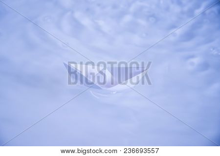 Small Folded Paper Ship On White Water As Symbold For Transportation And Tourism
