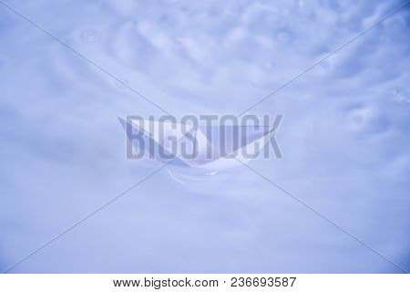 small folded paper ship on white water as symbold for transportation and tourism