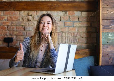 Young Woman Showing Thumbs Up Near Modern Laptop. Concept Of Seccussful Businesswoman And Modern Tec