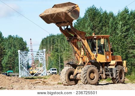 Wheel loader machine unloading sand at eathmoving works at construction site