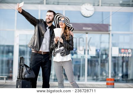 Young Couple Of Travelers In Leather Jackets Making Selfie Photo Standing In Front Of The Airport Te