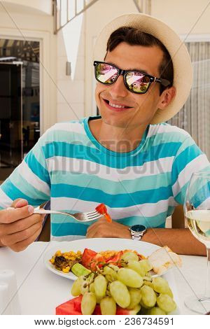 Happy Young Man Eating Food In Hotel Restaurant. All Inclusive Concept. Summer Vacation. Having Lunc
