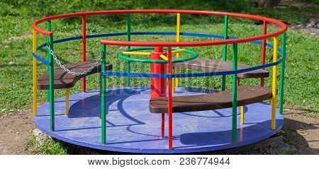 Children's Iron Carousel. Children's Playground. Swing, Carousel And Slide