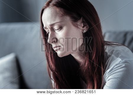 Difficult Year. Young Beautiful Sorrowful Woman Looking Down While Grumping And Posing In Profile