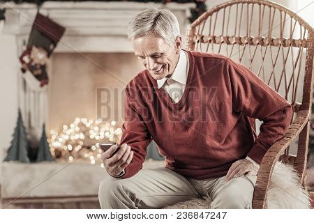 Reading Gratters. Delighted Man Keeping Smile On His Face And Bowing Head While Putting Left Hand On