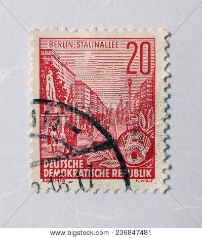 Leeds, England - April 18 2018: An Old East German Red Postage Stamp With A Street Scene Commemorati