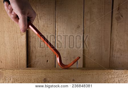 One Iron Nail And Nail Puller On A Wooden Background