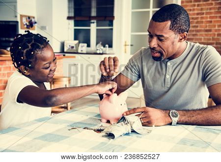 Dad and daughter saving money to piggy bank
