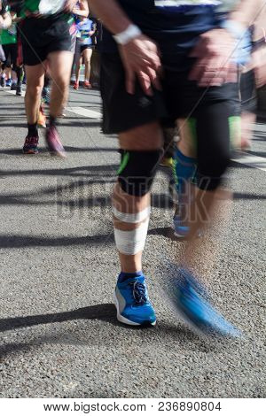 Front View Closeup Of Injured Marathon Runner With White Bandage On Leg And Motion Blur