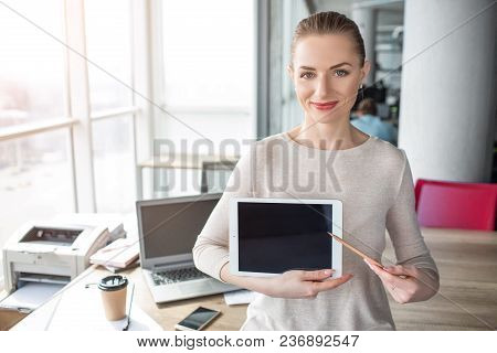 A Picture Of Happy And Cheerful Woman Having Laptop In Her Hands. She Has A Pen In Her Left Hand And