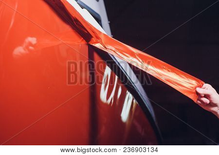 Car Wrapping Specialist Putting Vinyl Foil Or Film On Car. Selective Focus.