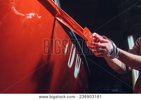 Car Wrapping Specialist Putting Vinyl Foil Or Film On Car. Selective Focus.