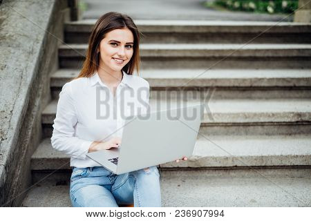 Smiling Student Girl Sitting On Stairs Working With Laptop, Preparing For Exams Outdoors, Having Res